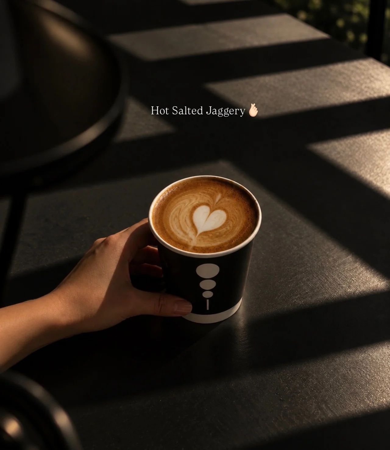 A cup of KAFI coffee held in warm sunlight